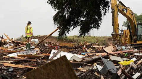 Getty Images Workers operate heavy machinery to clear debris after massive flooding