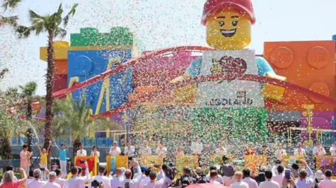 Reuters Confetti fills the air as a crowd gathers near a stage in front of a towering Lego mascot statue during the grand opening ceremony of Legoland Shanghai Resort in Shanghai, China, on 5 July.
