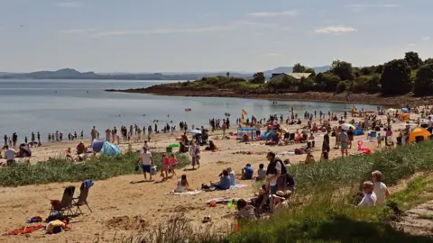 Getty Images Many people sit on towels at the Silver Sands beach at Aberdour on a sunny day