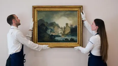Sotheby's Two Sotheby's workers, one man and one woman, both wearing white smart shirts, gloves and dark aprons, hold the painting in a frame as though they are mounting it to a wall. It is housed in a golden gilt frame, and mostly consists of dark blues, greys and greens.