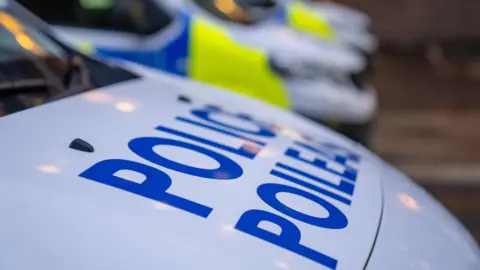 BBC A Police Scotland van parked at the side of a road. It has blue and florescent yellow markings on the side, and a large blue Police Scotland logo