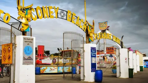 Getty Images Entrance gates to amusement park with Coney Beach Pleasure Park in yellow letters on top of the gates and attractions visible behind 