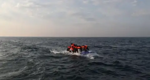 GARETH FULLER/PA A dinghy on cross a rough English Channel with several people onboard with orange life jackets. 