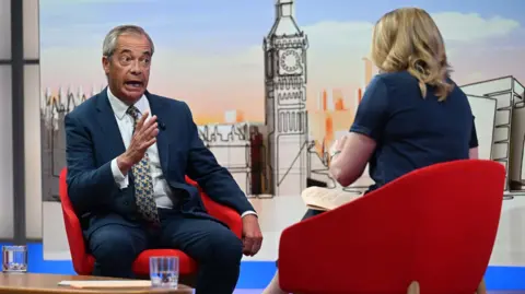 Jeff Overs/BBC Nigel Farage being interviewed in a TV studio by the BBC's Laura Kuenssberg, who has her back to the camera.
