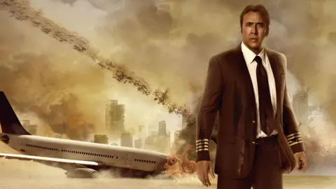 Stoney Lake/Gonella Prods/Kobal/Shutterstock A promotional composite image showing Nicolas Cage in a pilot's uniform standing in front of a crashed plane