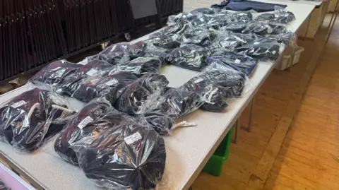 George King/BBC A table with bagged-up school uniform items on it