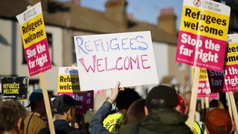 EPA "Refugees welcome" banners and the back of counter protesters heads