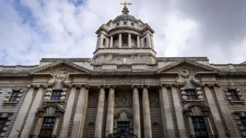 Getty Images Old Bailey court. Classical-style pillars stand at the front of the pale stone building with a raised dome at the centre topped with a gold-coloured statue holding the scales of justice