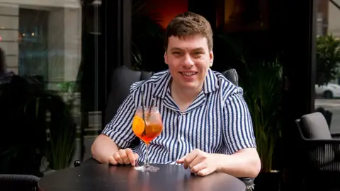 BBC Alex waiting outside a bar with a cocktail