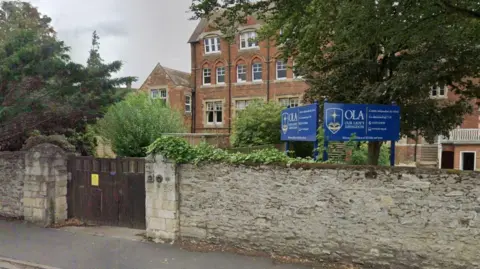 BBC A Google Maps closeup of the front of red brick private school. A wall sits in front of the building with a school gate to the left, and a sign for the school rests just above the wall.