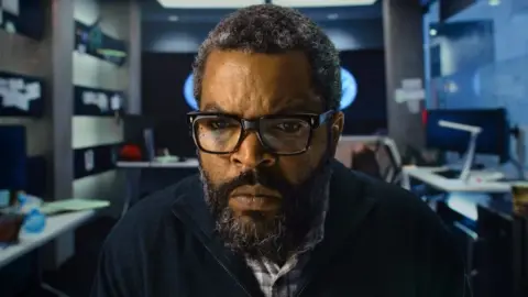 Universal Pictures/Prime Video Ice Cube in an office facing the camera and staring intently at a screen