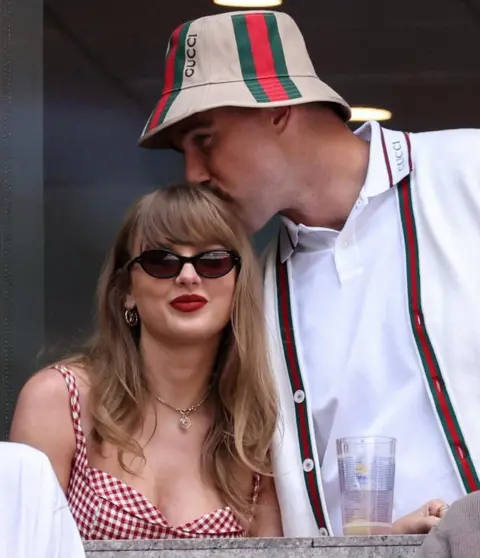 Reuters Man kisses the top of woman's head as she sits down
