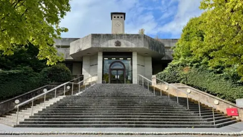 A view up some steps towards Newport Crown Court, which is an eggshell colour and has a large clock tower