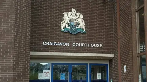Google maps A screen grab of a brown brick building with a silver coat of arms and silver writing that says 'Craigavon Courthouse'.