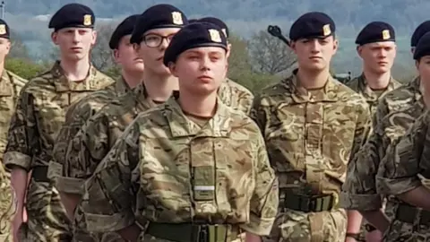Family Handout Gunner Beck stands in a group of uniformed soldiers