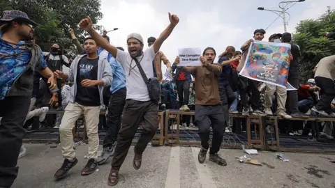 Getty Images People cheer in the street, one of them holding a piece of paper that says "Stop corruption save Nepal!"