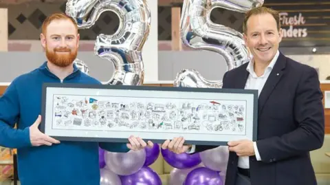 Meadowhall Luke Horton (left) holds a small version of the mural he was commissioned to create on the wall near Oasis food court