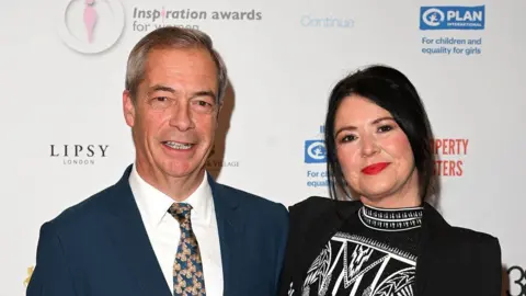 Getty Images Nigel Farage, in a suit and tie, poses for the cameras with Laure Ferrari, at the 2024 Inspiration for Women awards
