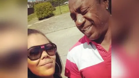 Natalie Douglas A selfie of Natalie and her dad Anthony, She is wearing sunglasses and has dark hair with some of it pulled back. Anthony is looking at his daughter and smiling, he has an earring and is wearing a red and white striped shirt.