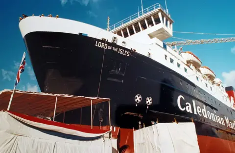 Ferguson Shipbuilders A black and white ship with red paint below the keel, about to be launched from a slipway