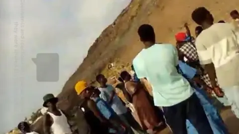 James Nunan/Facebook A still taken from James Nunan's Facebook Live broadcast. It shows people gathered on a beach.