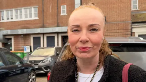 Woman standing in a car park.