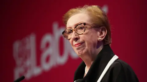 PA Media Dame Margaret Beckett stands in front of a Labour party logo
