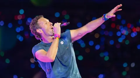 Getty Images Chris Martin of Coldplay stretches his hand out to the audience during a Coldplay show at Wembley Stadium
