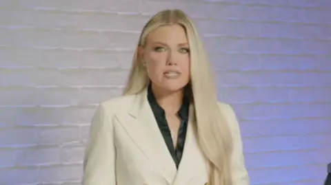 Turning Point USA Screenshot of Erika Kirk. She has long blonde hair and is wearing a white blazer with a black shirt underneath.