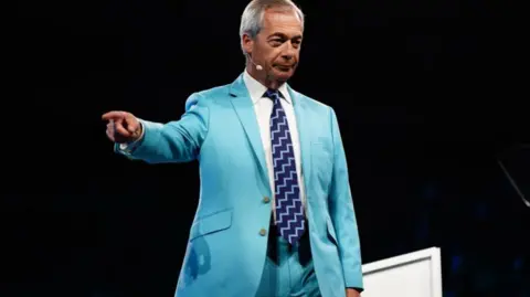 PA Media Reform UK leader Nigel Farage points off stage as he addresses the party's conference at the National Exhibition Centre in Birmingham