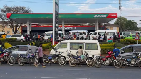 BBC A wide view of a petrol station jammed with cars. Vehicles can also be seen on the road in front - all waiting to enter.