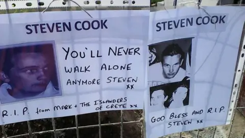 Handout Posters of Steven Cook put up on a metal fence after his remains were found in 2017, one says 'You'll Never Walk Alone Anymore Steven, RIP from Mark and the Islanders of Crete"
