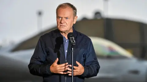 Reuters A man in a navy jacket stands in front of a microphone