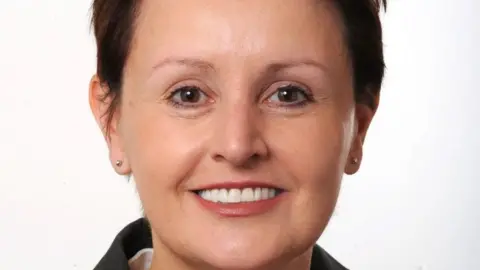 Glasgow City Council Annemarie O'Donnell smiles into the camera - she has short brunette hair and a dark jacket on