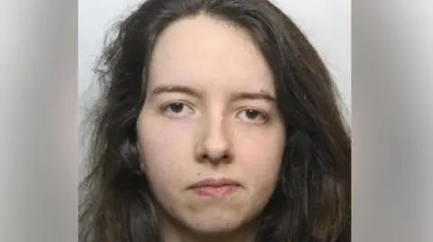 South Yorkshire Police A mugshot of a woman with a neutral expression, bushy brown hair and brown eyes.