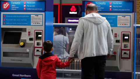 Getty Images A father and son buying tickets at a machine in a train station