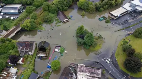 Athena Drone footage showing flooding around a roundabout in an estate in Wales.