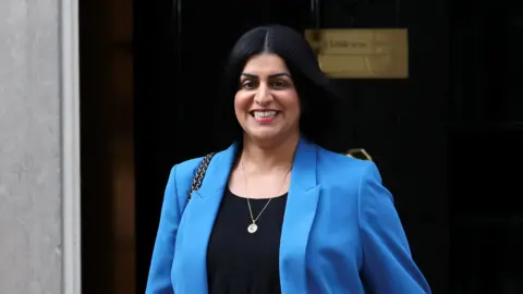 Reuters Shabana Mahmood, walking down Downing Street, smiling and wearing a blue blazer.